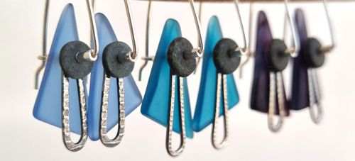 Sea glass and river pebble earrings in blue, teal and purple hanging from a driftwood branch