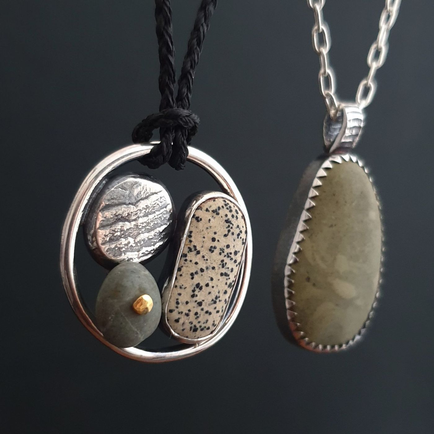 Two river stone pendants in sterling silver settings on a dark background