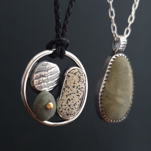 Two river stone pendants in sterling silver settings on a dark background