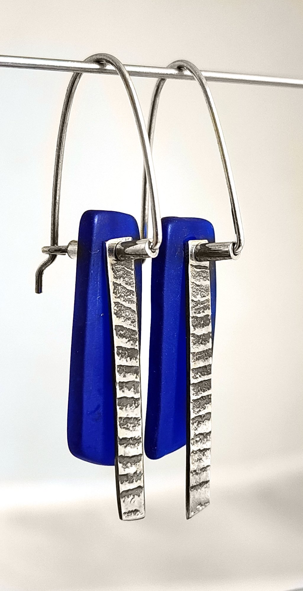 Deep blue tumbled glass earrings with sterling silver hooks and textured pendant detail